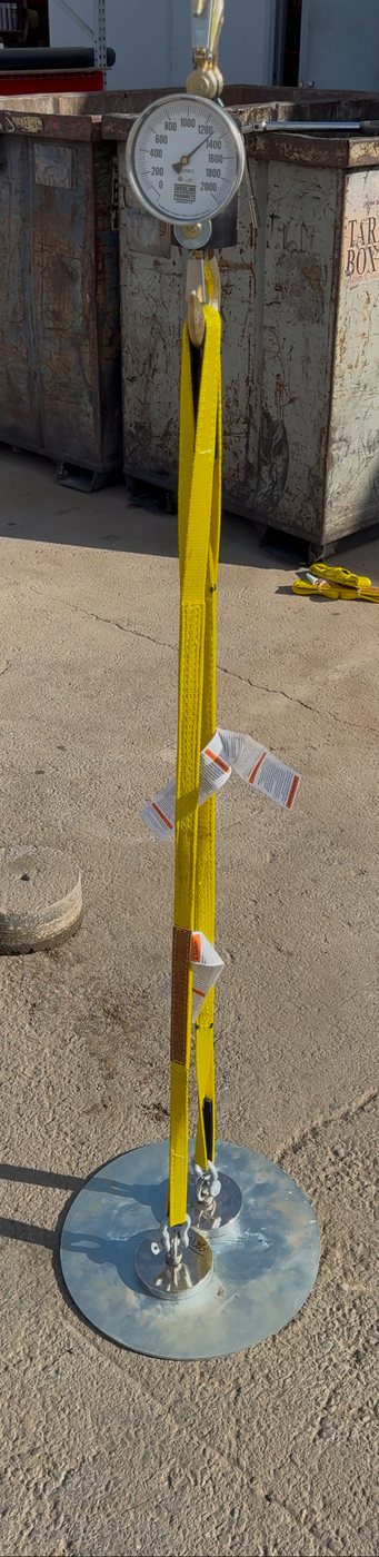 Core Cap installed in pavement under direct uplift test — gauge, strap, and core sample visible